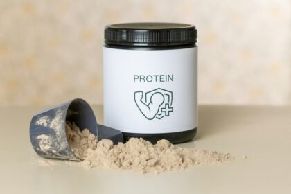 Sporcu beslenmesi konseptinde, bir kutu protein tozu, shaker, dambıl ve muzdan oluşan, kas gelişimi için sağlıklı ve etkili takviyeler.